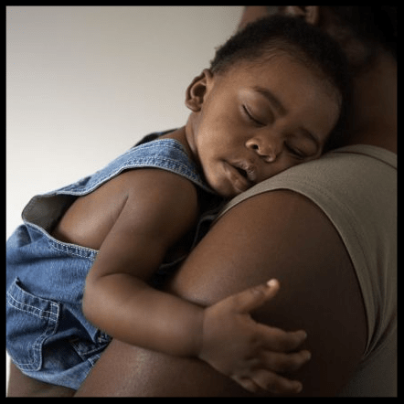a small child asleep on a mother's shoulder.